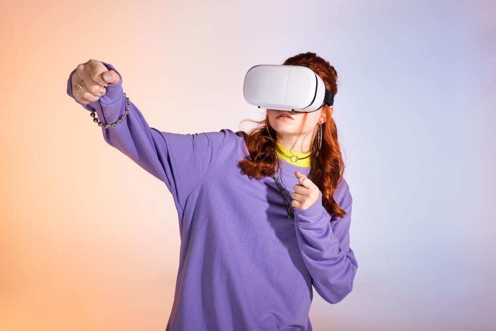 emotionale Teenie-Mädchen gestikulieren und Virtual-Reality-Headset verwenden, auf lila und beige  - Foto, Bild