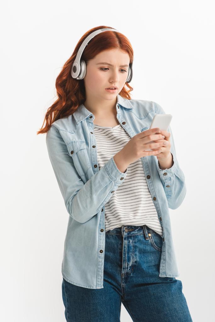 schönes Teenie-Mädchen, das Musik mit Kopfhörern und Smartphone hört, isoliert auf weiß - Foto, Bild