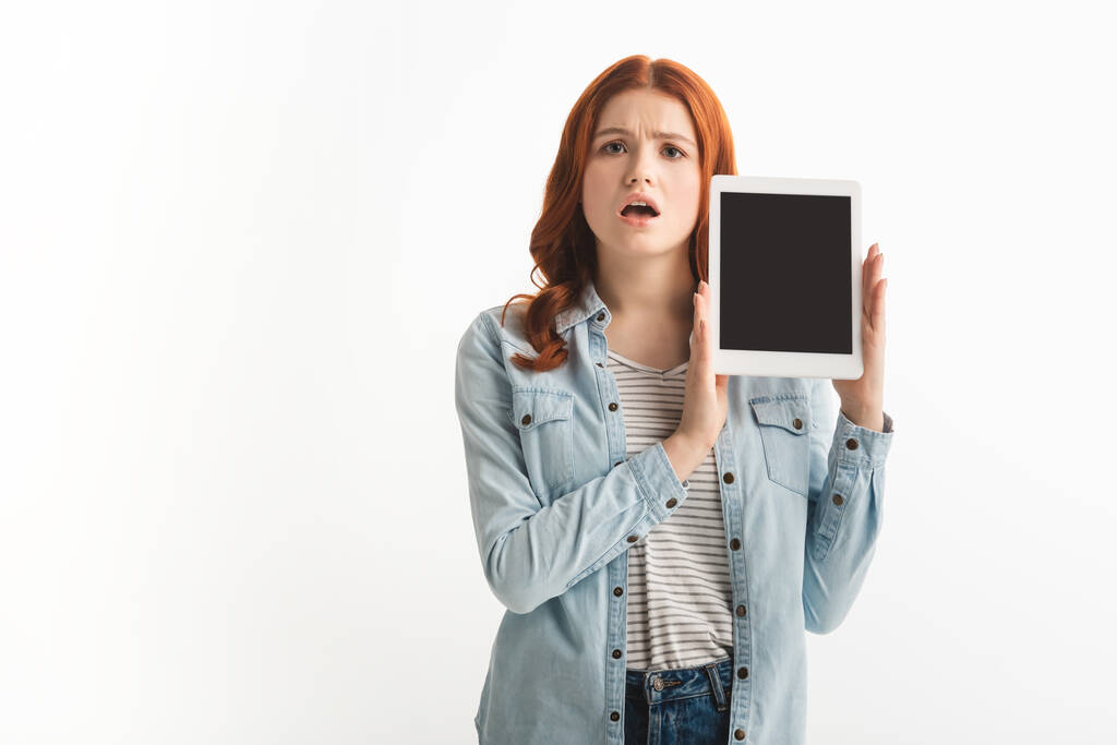Güzel, şok olmuş genç bir kız beyaz ekranlı dijital tablet gösteriyor. - Fotoğraf, Görsel
