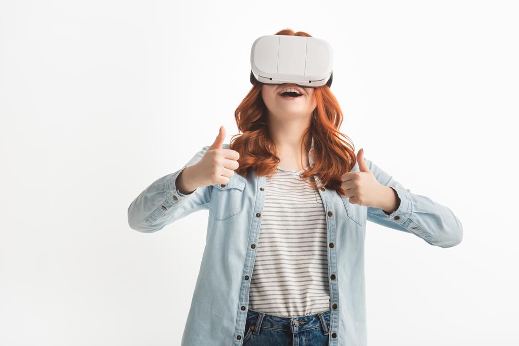 excited redhead teenager showing thumbs up and using virtual reality headset, isolated on white - Photo, Image