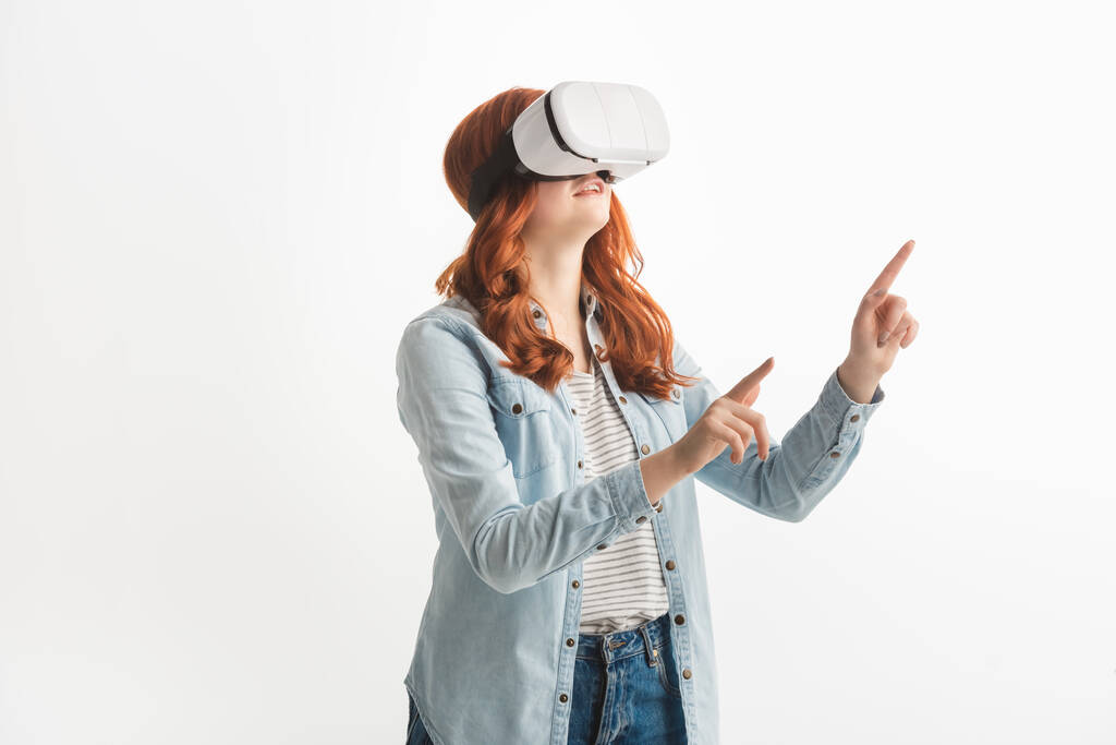 mooie emotionele roodharige tiener gebaren en met behulp van virtual reality headset, geïsoleerd op wit - Foto, afbeelding