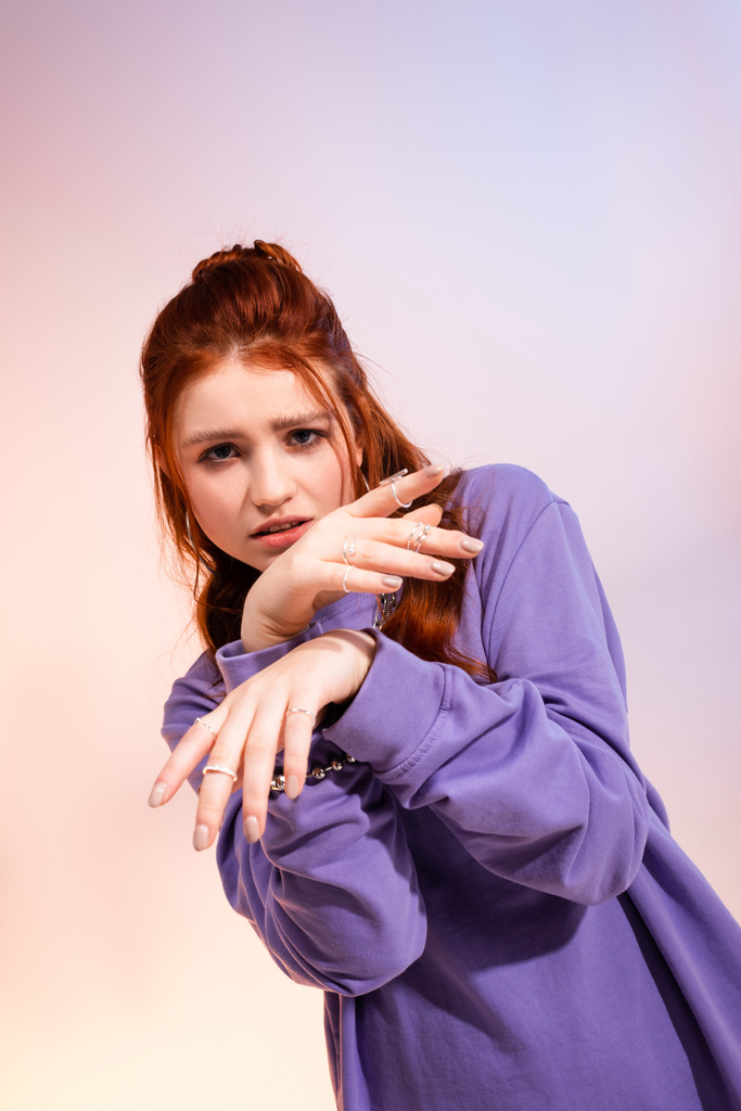 beautiful redhead teen girl in bad mood, on purple and beige  - Photo, Image