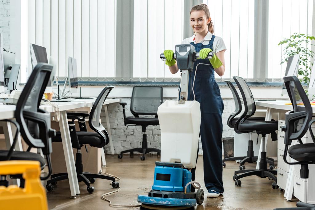 Lächelnder sauberer Waschboden im Büro mit Reinigungsmaschine - Foto, Bild