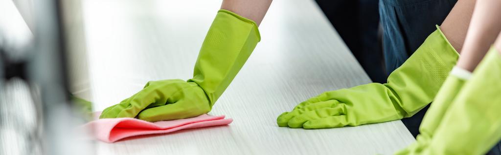 vista recortada de limpiador en guantes de goma lavado escritorio de la oficina
 - Foto, Imagen