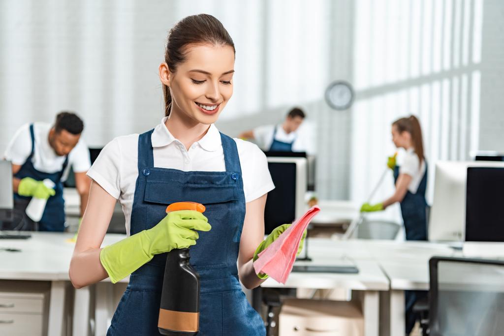 attractive, smiling cleaner spraying detergent on rag - Photo, Image