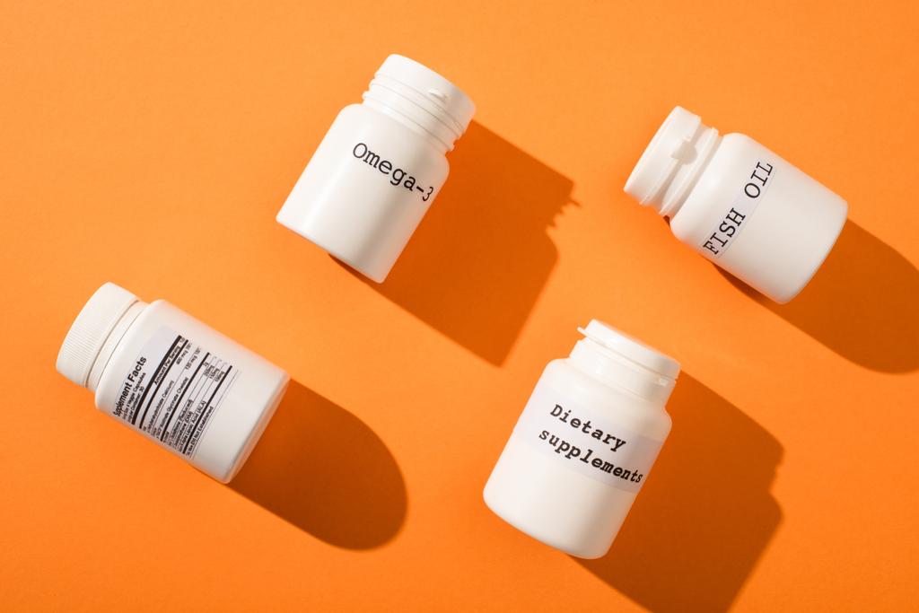 Lapos feküdt konténerek omega-3, halolaj és étrend-kiegészítők felirat narancssárga alapon - Fotó, kép