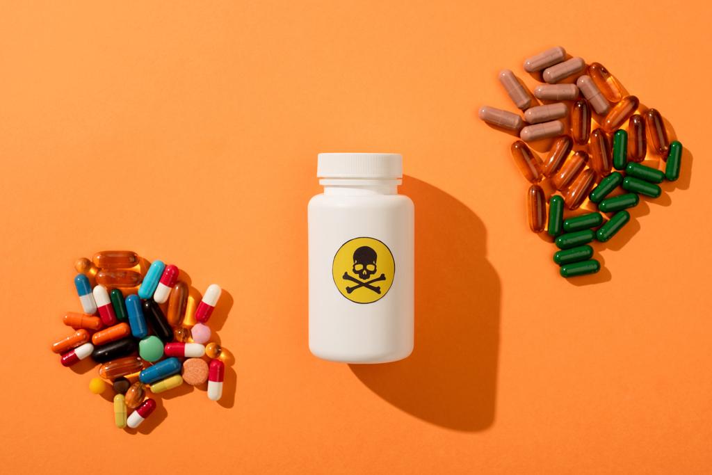 Κάτοψη δοχείου με επικίνδυνο δηλητήριο και συμπληρώματα διατροφής σε πορτοκαλί φόντο - Φωτογραφία, εικόνα