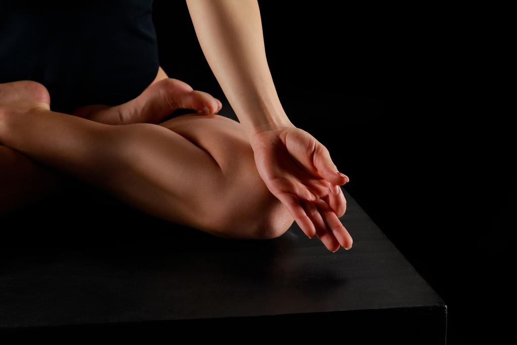 vista ritagliata della donna in posa di loto praticare yoga isolato su nero
  - Foto, immagini