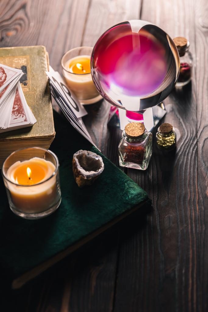 KYIV, UKRAINE - JANUARY 9, 2020: selective focus of crystal ball, books, candles and occult objects on wooden background - Photo, Image