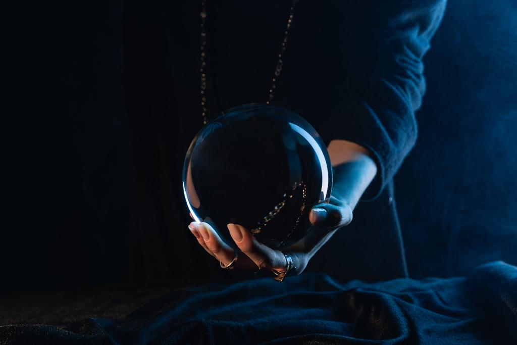 Vista parziale della sfera di cristallo in mano femminile su blu scuro
 - Foto, immagini