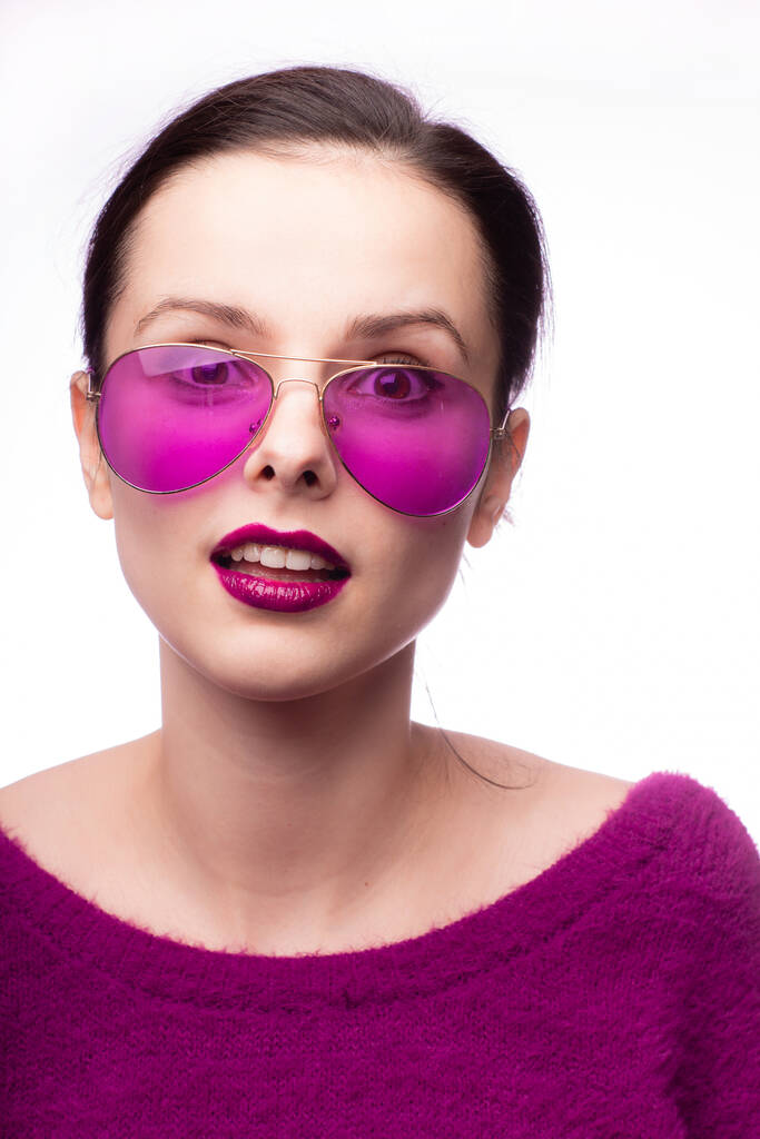 meisje in een paarse trui, paarse bril met paarse lippenstift op haar lippen - Foto, afbeelding