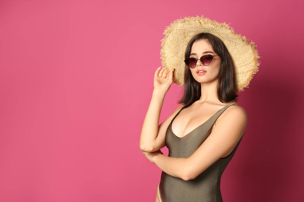 Bella giovane donna che indossa costume da bagno, cappello e occhiali da sole su sfondo rosa. Spazio per testo
 - Foto, immagini