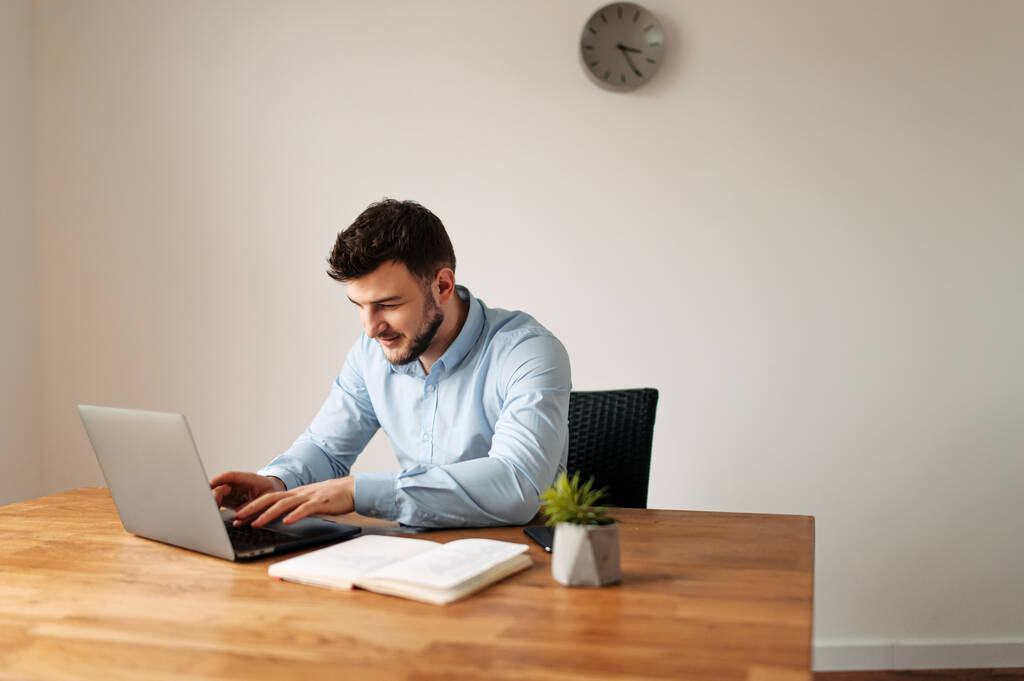 Trabalhador de escritório masculino atraente está usando um laptop
 - Foto, Imagem
