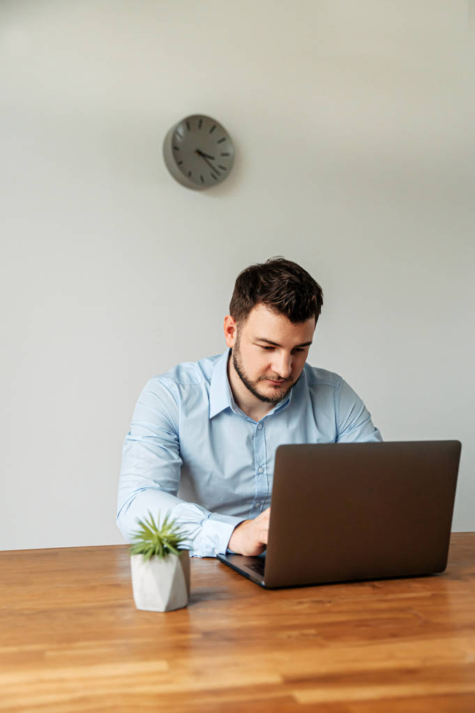 Aantrekkelijke mannelijke kantoormedewerker gebruikt een laptop - Foto, afbeelding