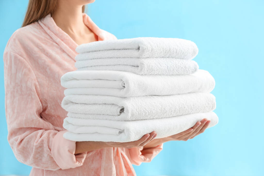 Frau hält Stapel frischer sauberer Handtücher auf hellblauem Hintergrund, Nahaufnahme - Foto, Bild