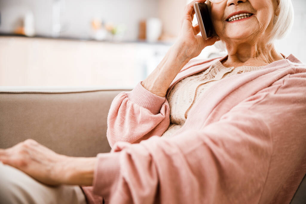 Senior vrouw praten op mobiele telefoon en glimlachen - Foto, afbeelding