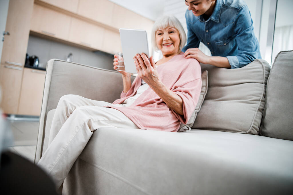 Starsza pani korzystająca z tabletu cyfrowego i spędzająca czas z wnuczką - Zdjęcie, obraz