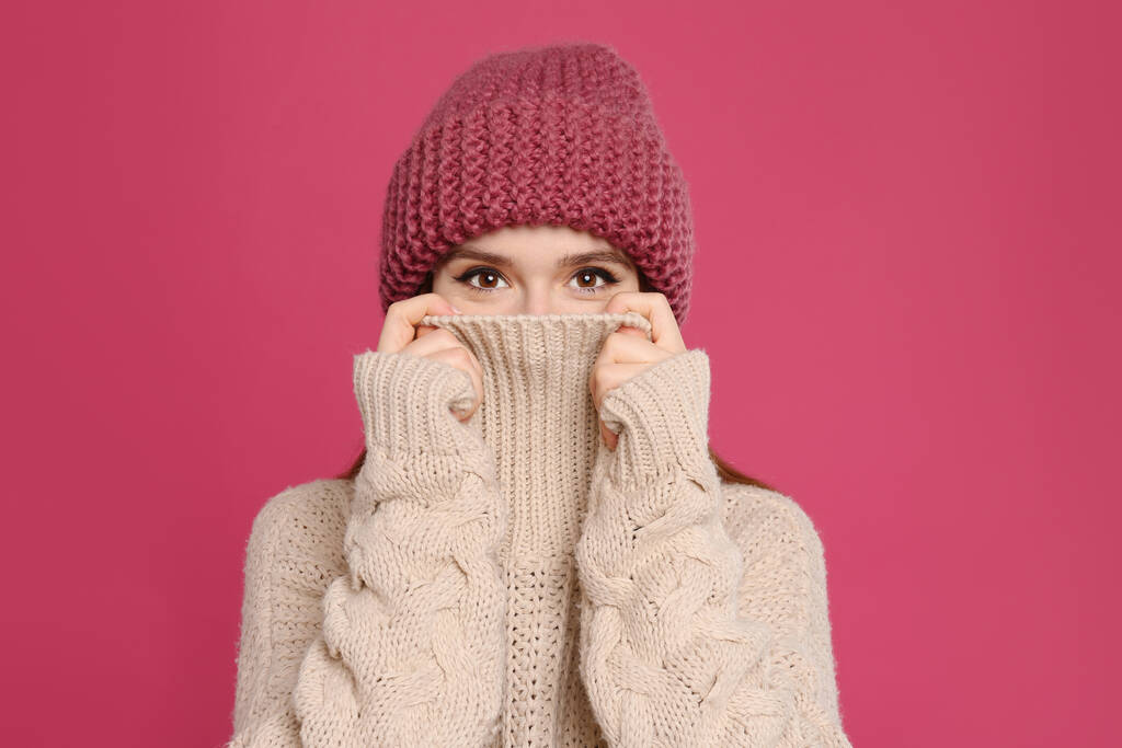 Mujer joven con suéter cálido y sombrero sobre fondo carmesí. Temporada de invierno
 - Foto, imagen