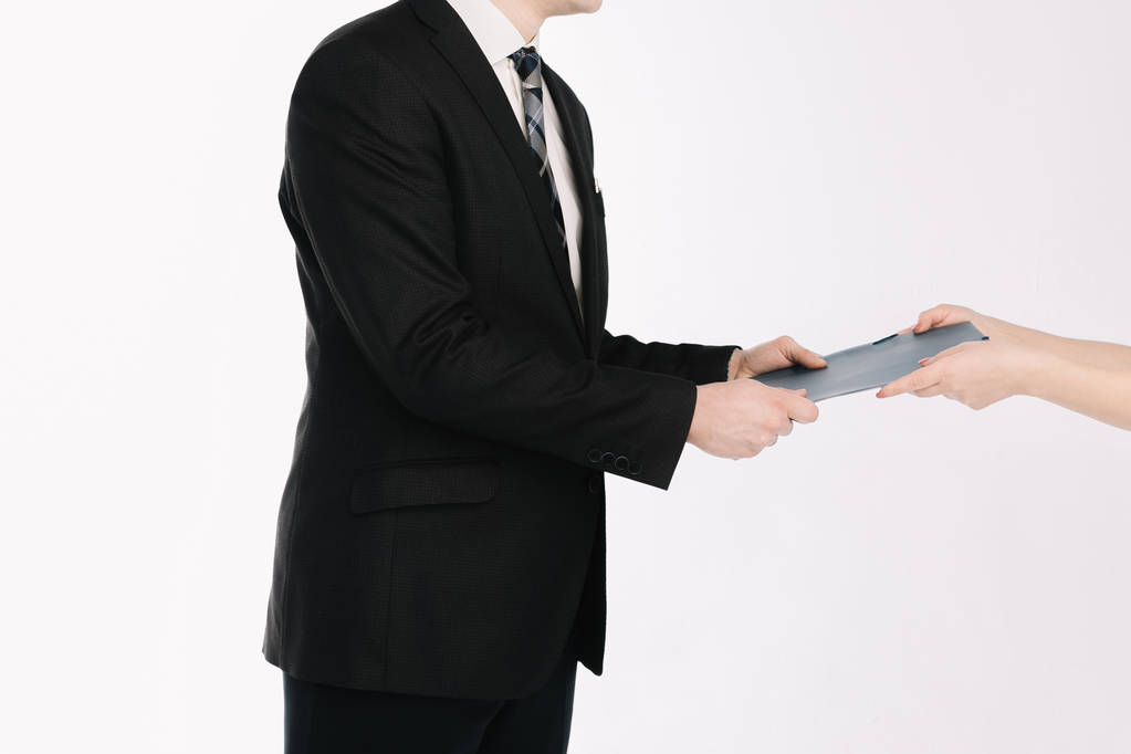 Um homem de negócios em um terno passa um documento em um fundo branco
. - Foto, Imagem
