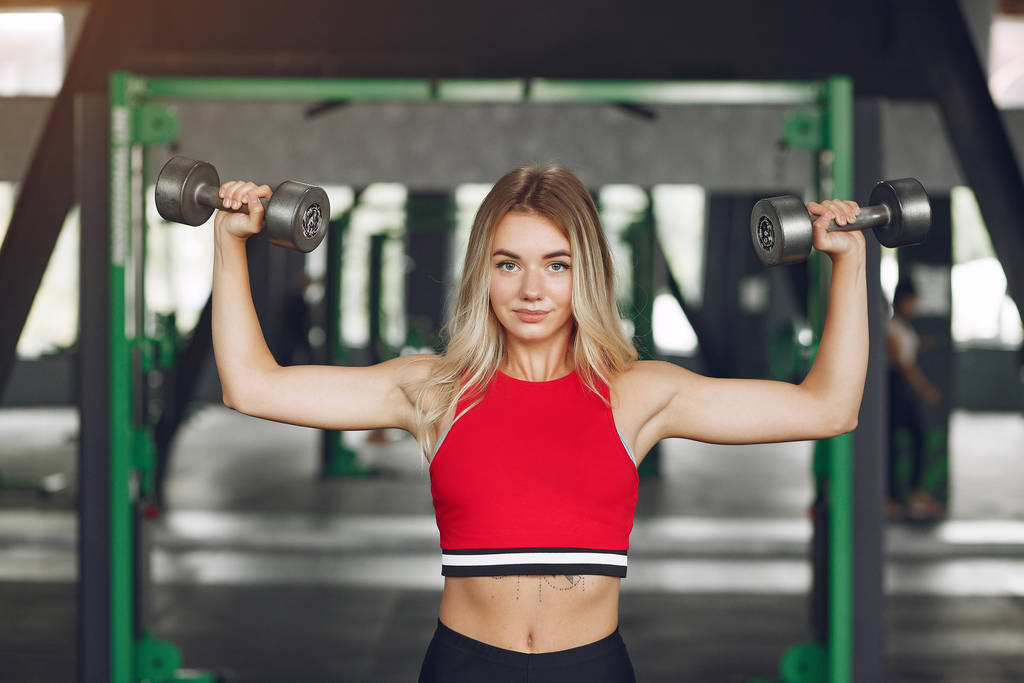 Sports blonde in a sportswear training in a gym - Photo, Image