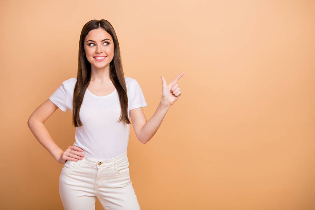 Portrait of positive cheerful girl promoter point index finger copyspace recommend adverts direct promotion wear casual style outfit isolated over beige color background - Fotoğraf, Görsel