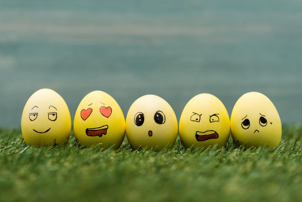 Húsvéti tojás különböző arckifejezésekkel a fűben  - Fotó, kép