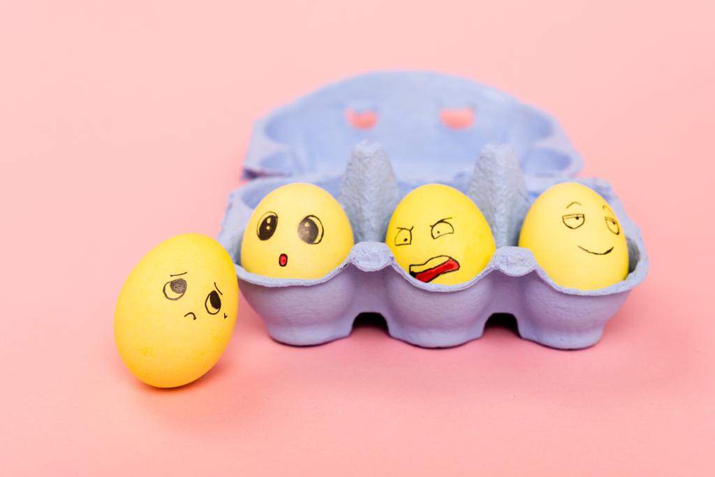 Selektiver Fokus von Ostereiern mit Gesichtsausdruck im Eierfach auf rosa Hintergrund - Foto, Bild