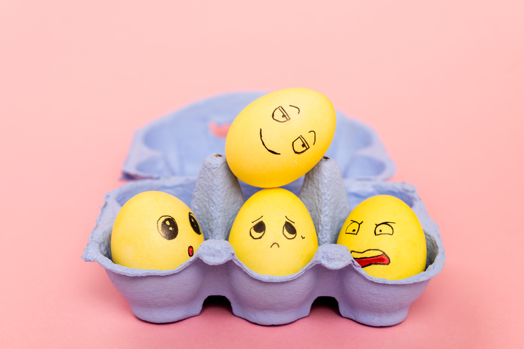 Επιλεκτική εστίαση των αυγών του Πάσχα με εκφράσεις του προσώπου στο δίσκο αυγών σε ροζ  - Φωτογραφία, εικόνα