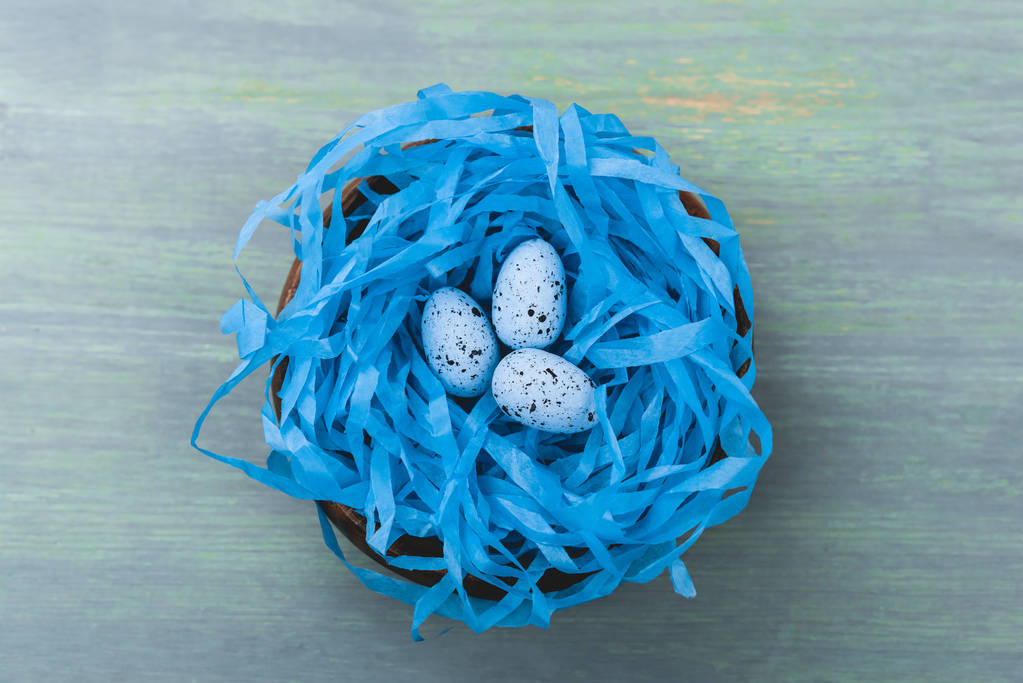 Top view of nest with painted quail egg on wooden background, easter concept - Photo, Image