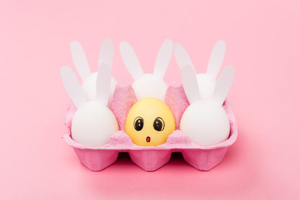 Decorative rabbits and yellow egg with surprised facial expression on pink, easter concept - Photo, Image
