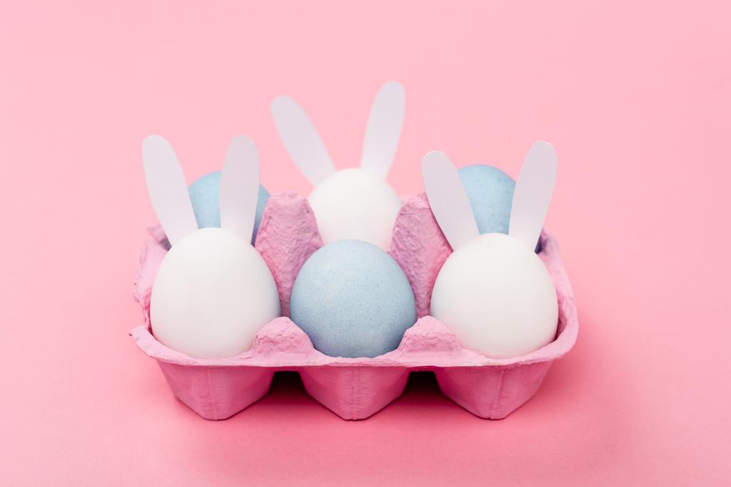 Dekorativní králíci a barevné velikonoční vejce na růžovém pozadí - Fotografie, Obrázek