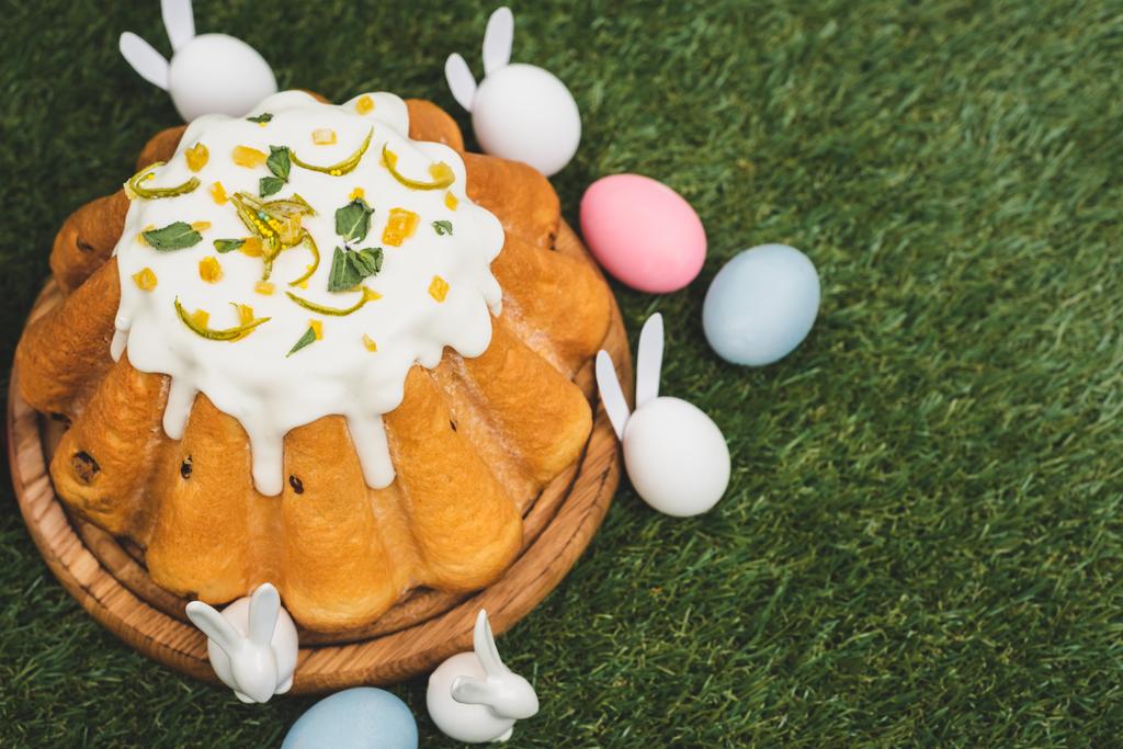 Vista de alto ângulo do bolo de Páscoa com ovos de galinha coloridos e coelhos decorativos no fundo verde
 - Foto, Imagem