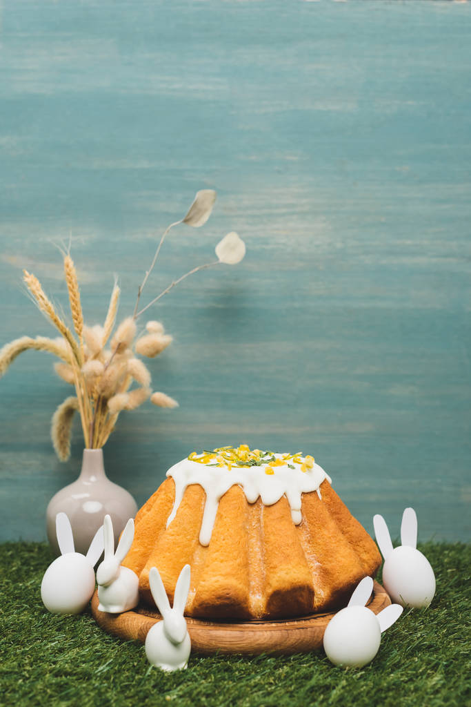 Húsvéti kenyér dekoratív nyulakkal és váza fűzfával és búzával a fűben - Fotó, kép