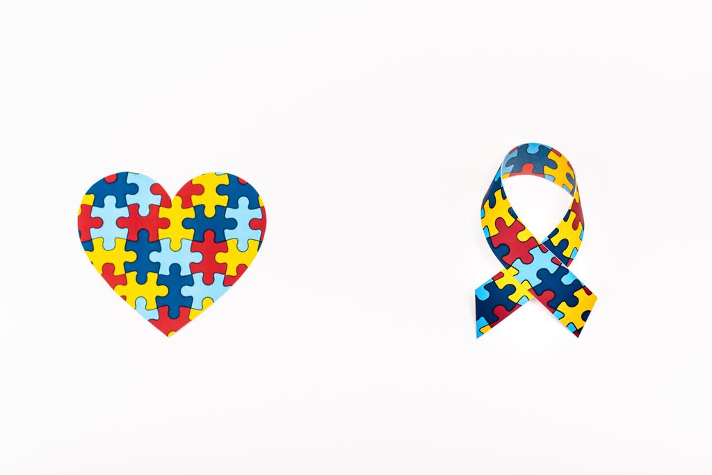 Vue du dessus du coeur de puzzle et ruban de sensibilisation isolé sur blanc, concept de l'autisme
 - Photo, image