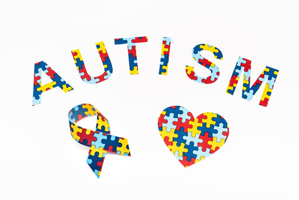 Vue grand angle de lettrage puzzle autisme, coeur décoratif et ruban de sensibilisation isolé sur blanc
  - Photo, image