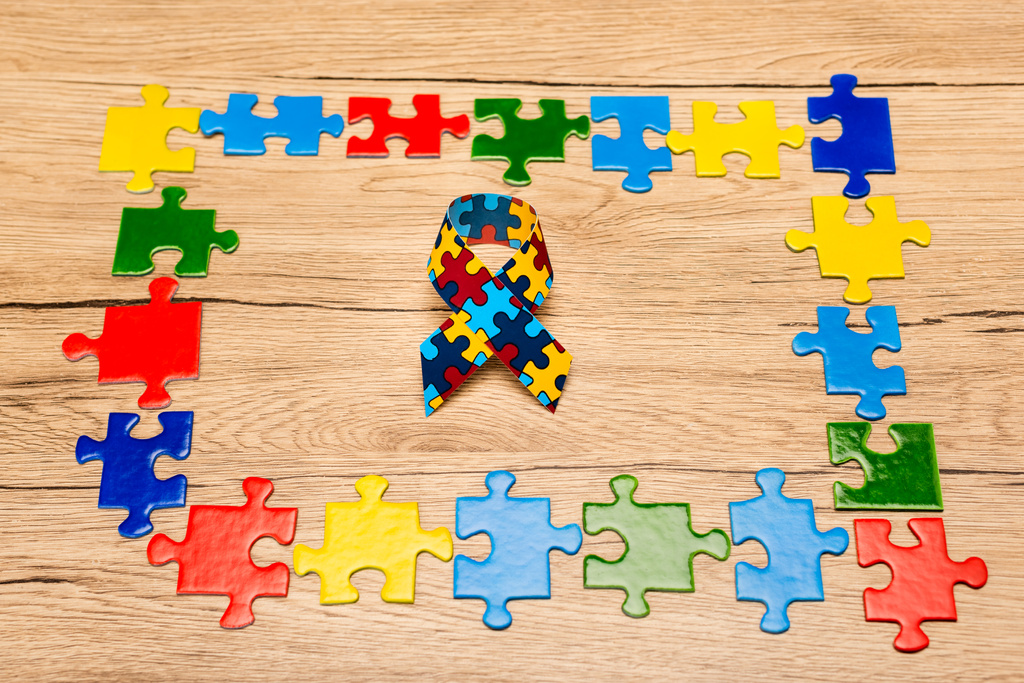 Hochwinkelansicht des Bewusstseinsbands mit bunten Puzzleteilen auf hölzernem Hintergrund, Konzept Autismus - Foto, Bild