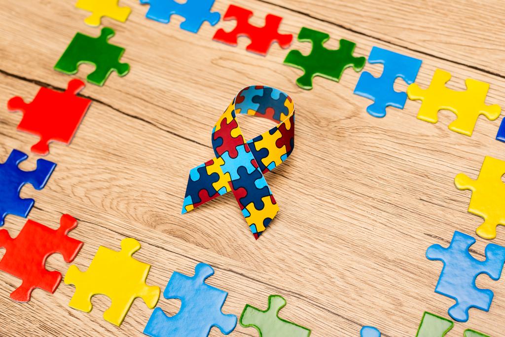 Hoge hoek van het bewustzijn lint met puzzelstukjes op houten achtergrond, autisme concept - Foto, afbeelding