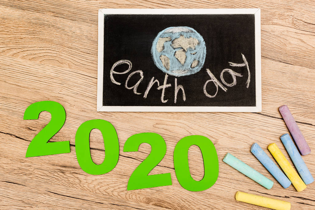 Vue du dessus de la planche avec lettrage jour terre, chiffres 2020 et morceaux de craie sur fond bois
 - Photo, image