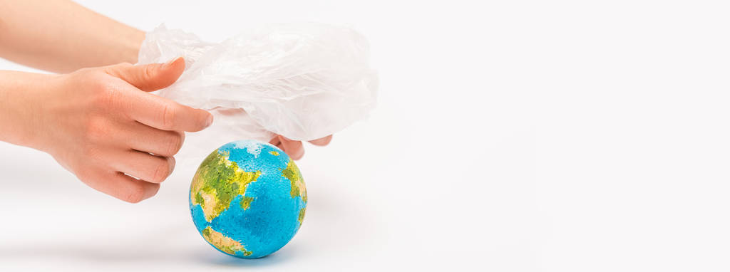 Vue recadrée de la femme tenant un sac en plastique au-dessus du globe sur le concept de réchauffement climatique blanc
 - Photo, image