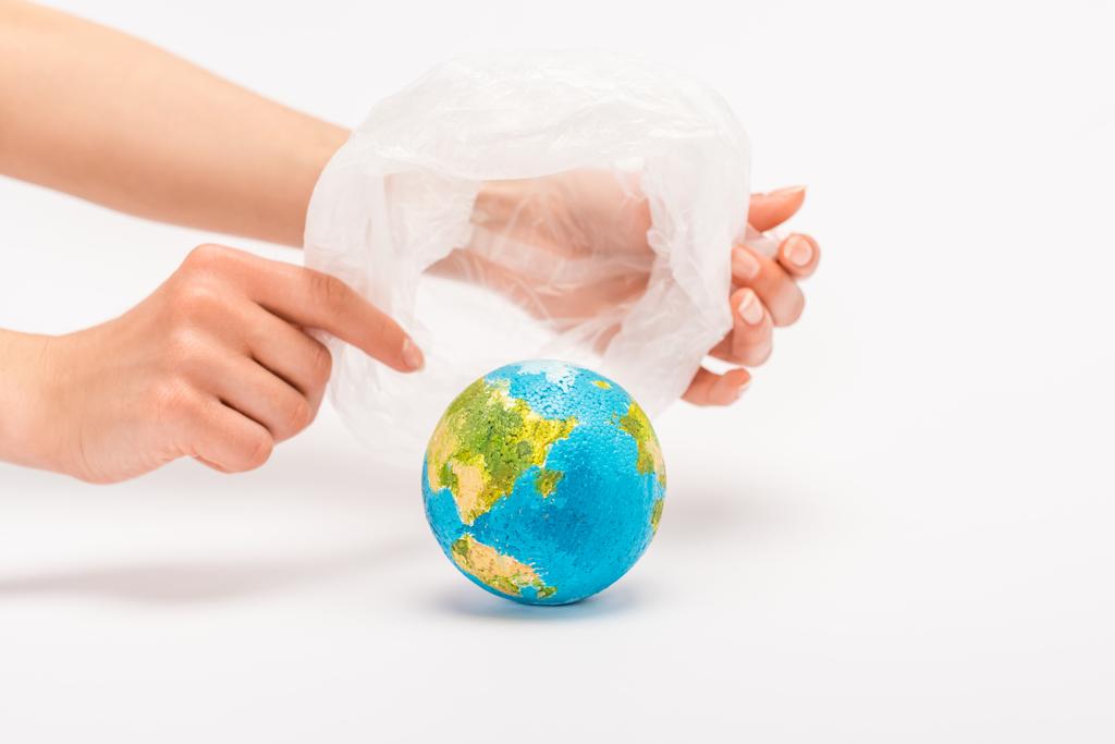 Vista parziale della donna che tiene il sacchetto di plastica sopra il globo sul bianco, concetto di riscaldamento globale
 - Foto, immagini