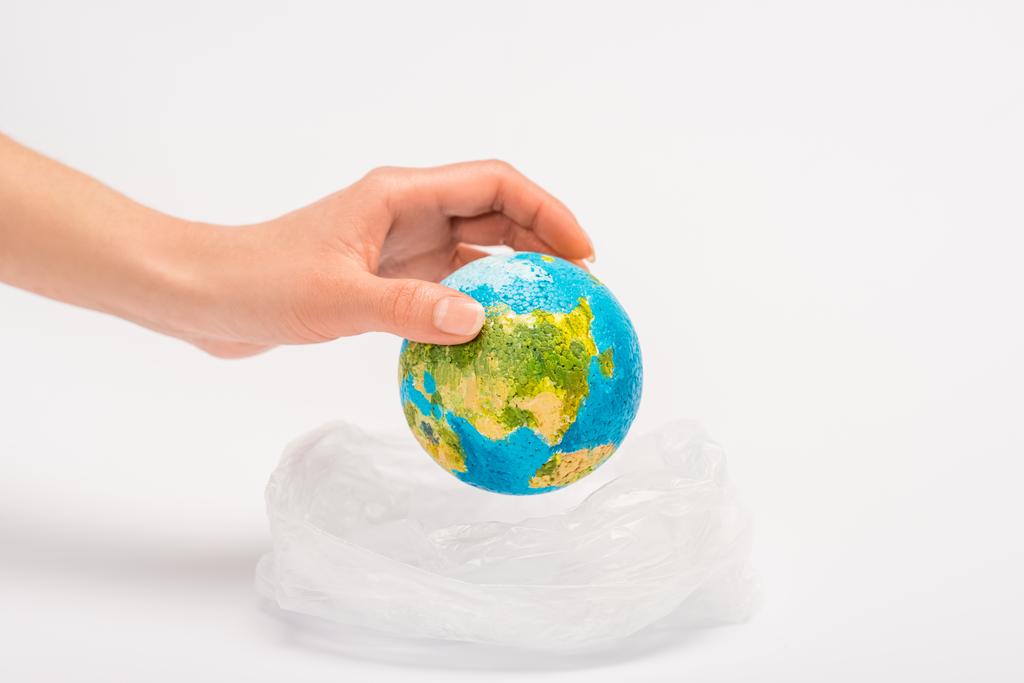 Vista ritagliata della donna che mette il globo in sacchetto di plastica sul bianco, concetto di riscaldamento globale
 - Foto, immagini