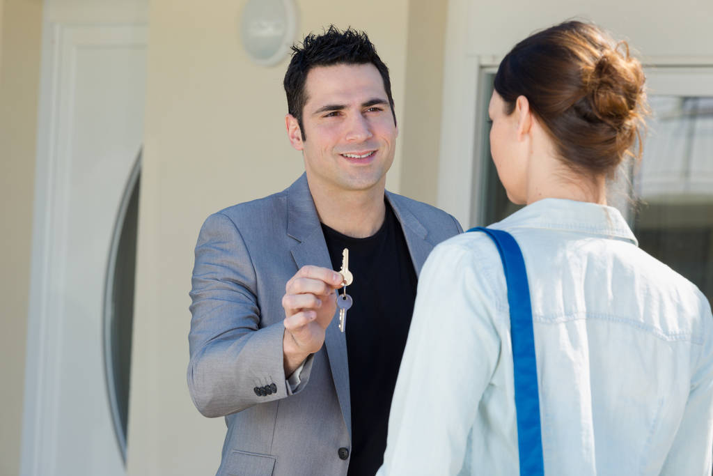 männlicher Makler übergibt Schlüssel an weiblichen Kunden - Foto, Bild