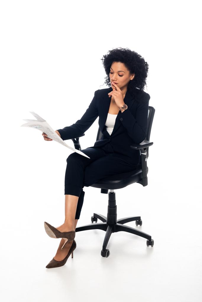 African american businesswoman in office chair reading newspaper on white background - Fotografie, Obrázek