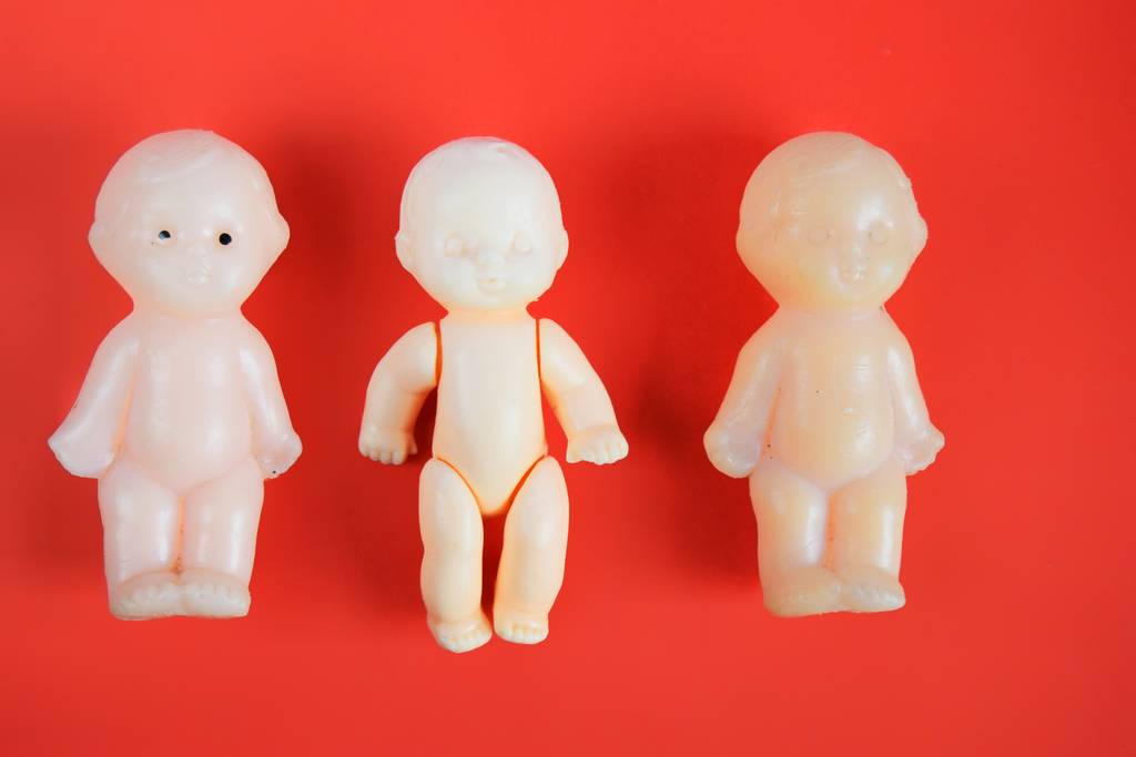 tre bambole di giocattoli da bambini per bambini a partire da un anno su uno sfondo rosso con un posto per l'iscrizione. vicino
 - Foto, immagini