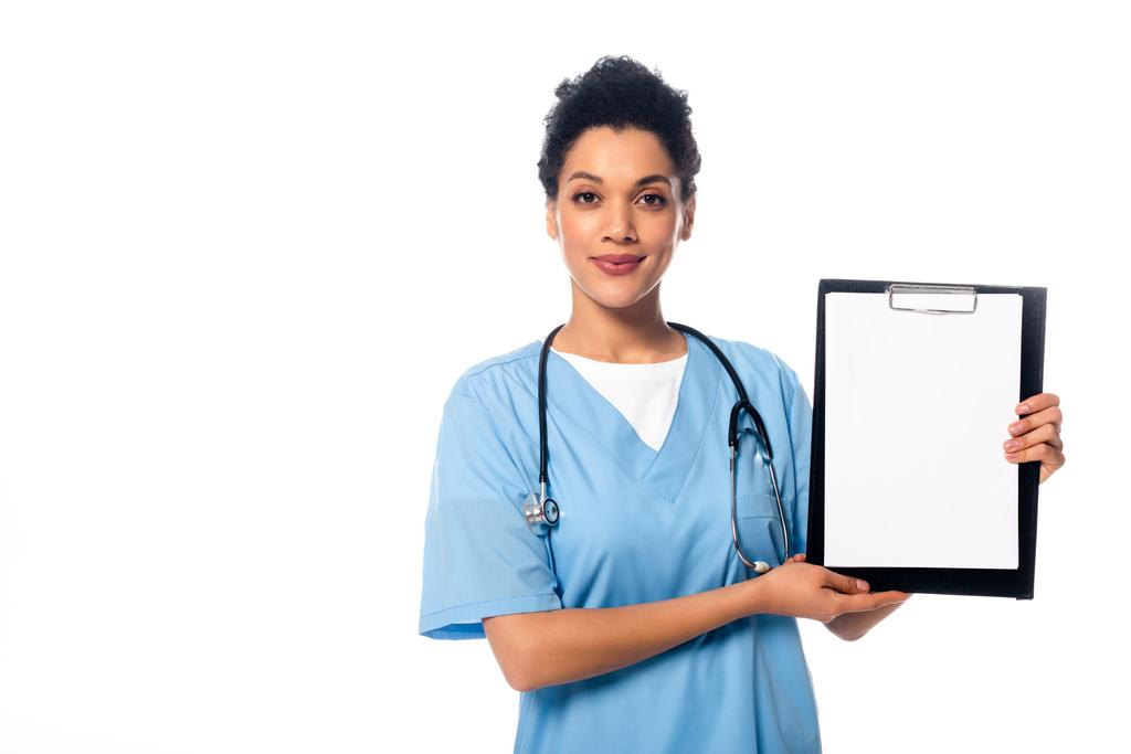 Vooraanzicht van Afro-Amerikaanse verpleegster met stethoscoop kijken naar de camera en tonen klembord geïsoleerd op wit - Foto, afbeelding