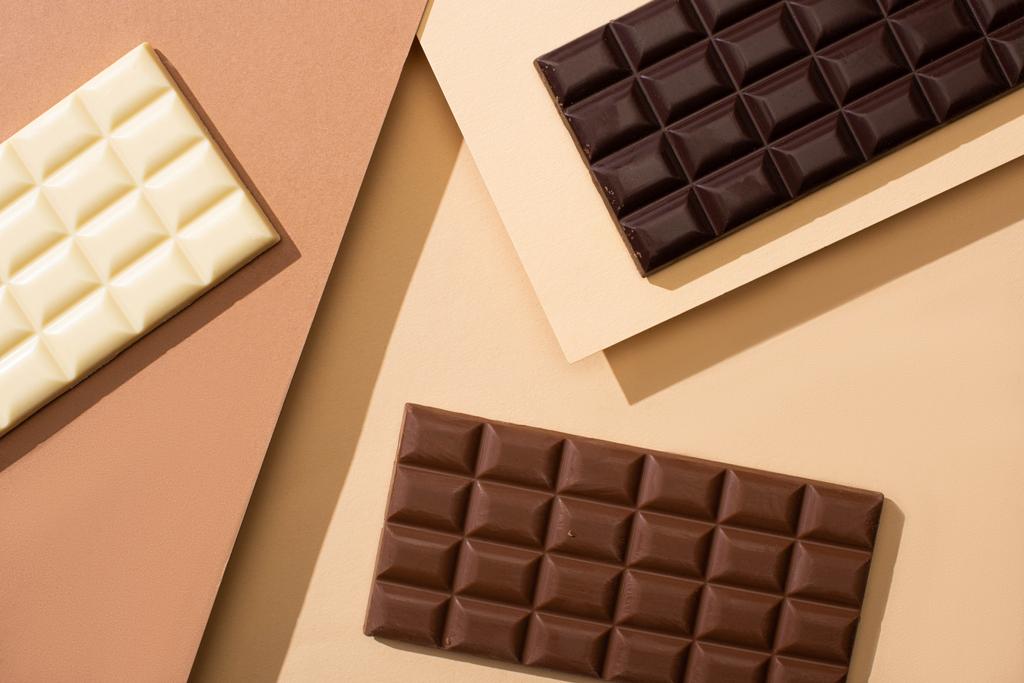 vue de dessus de délicieuses barres de chocolat blanc, au lait et noir sur fond beige
 - Photo, image