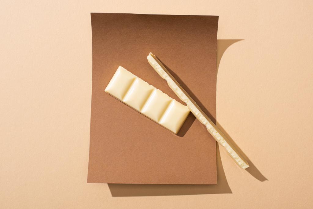 vista superior de deliciosas piezas de chocolate blanco en papel sobre fondo beige
 - Foto, Imagen