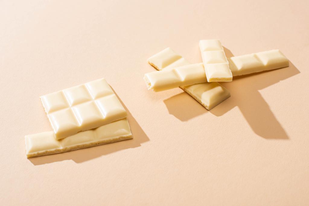сладкий вкусный сломанный белый шоколад на бежевом фоне
 - Фото, изображение