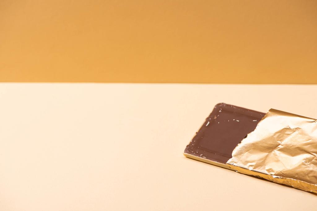 finom tejcsokoládé bar arany fólia bézs háttér - Fotó, kép
