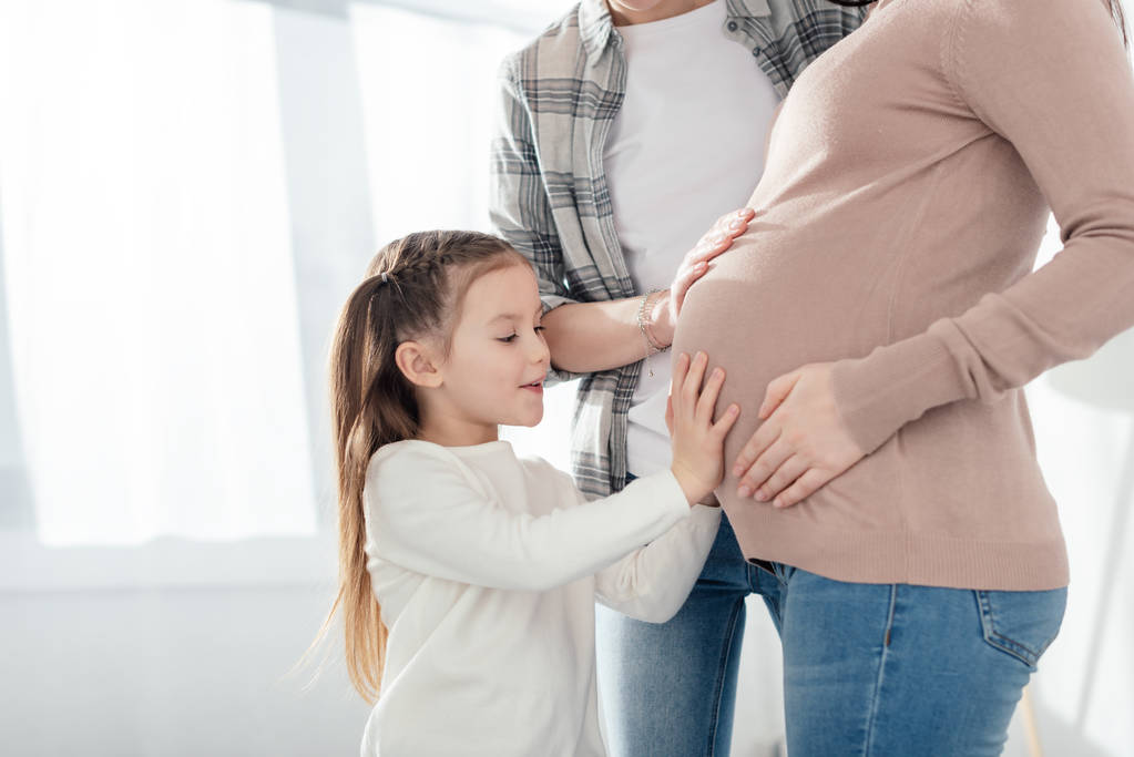居間で妊娠中の母親の子供と親に触れる腹 - 写真・画像